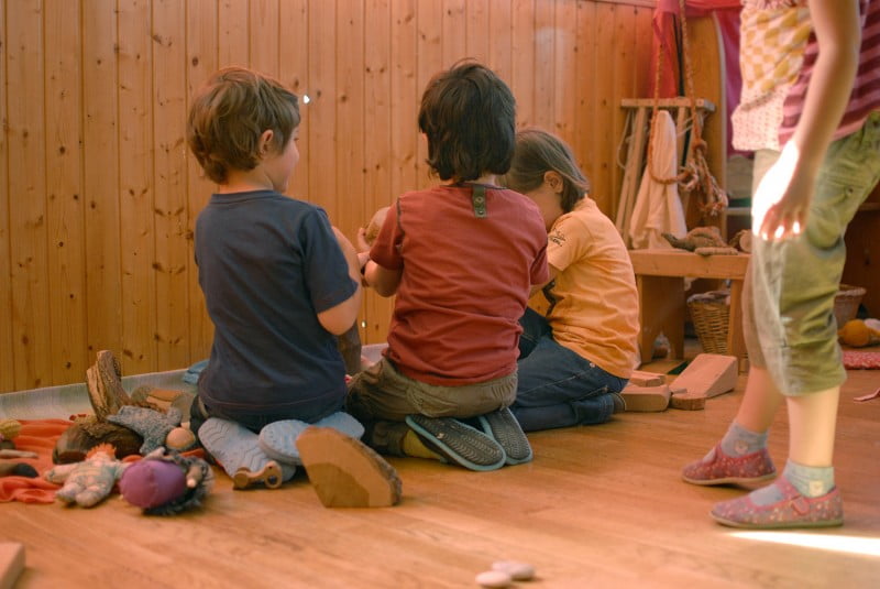 Tres niños jugando en el suelo con los juguetes Waldorf en el aula