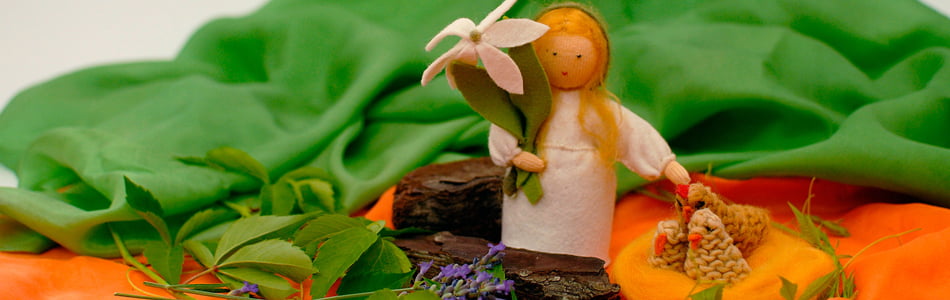 Niña hecha con fieltro que lleva una linda flor y representa la llegada de la Primavera