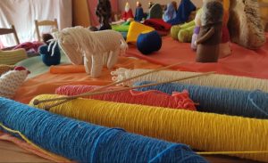 Madejas de colores de lana junto a juguetes para niños hechos con esas lanas