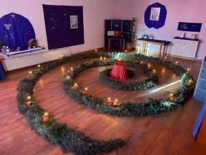Espiral hecha con arizonica y abeto con velas encendidas en el aula de la escuela infantil viendose la mesa de estacion